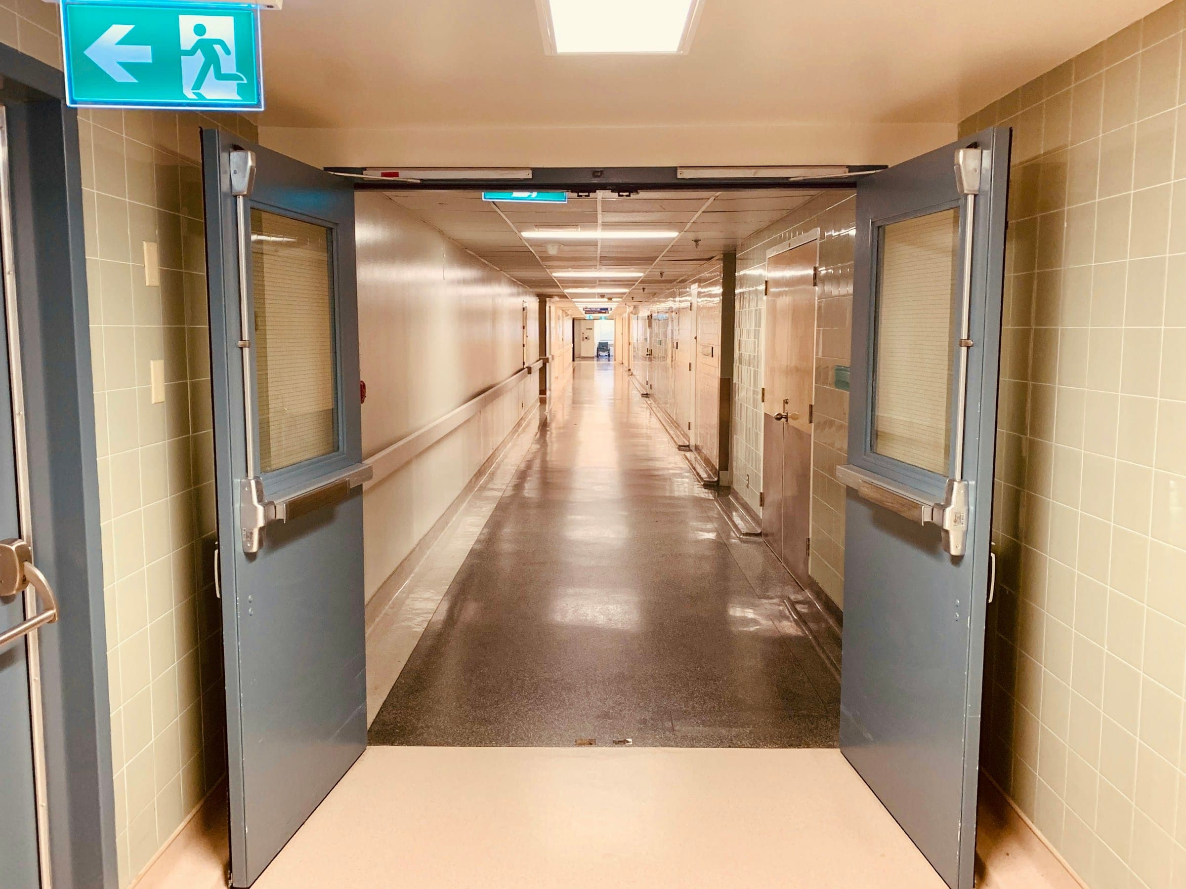 A long hospital corridor behind open double doors